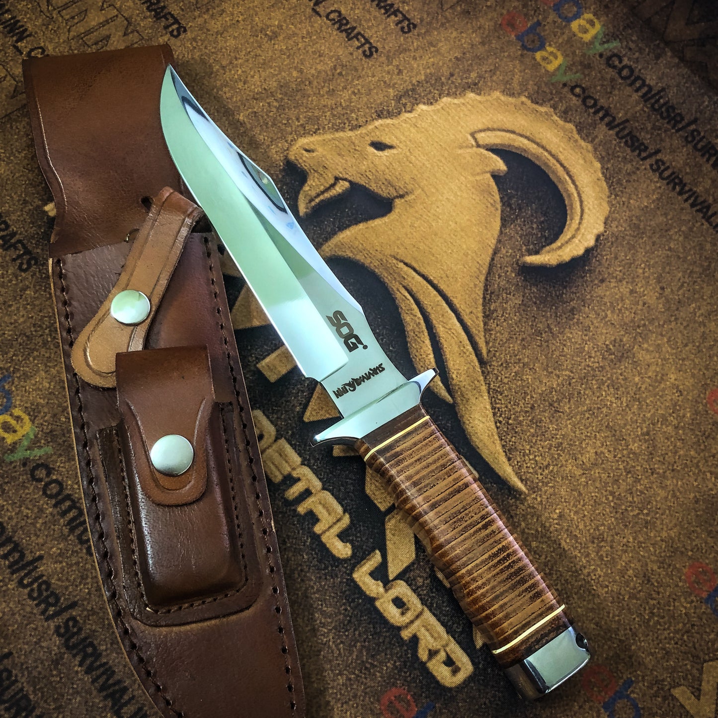 Sheathed handmade SOG knife next to its thick leather handle – perfect for collectors