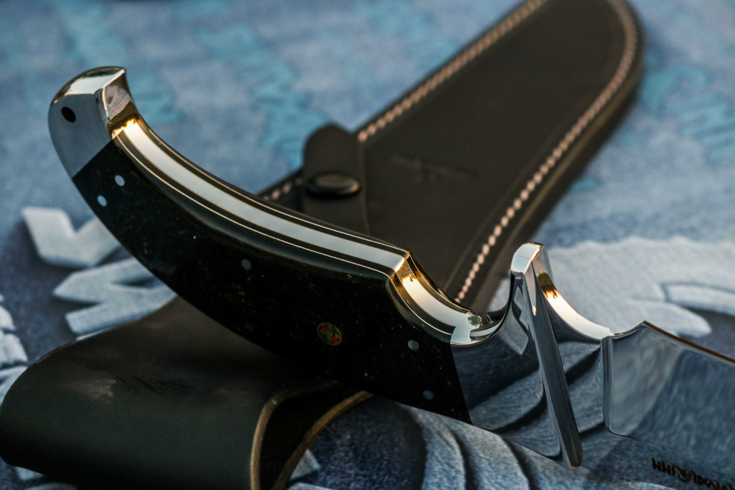 Galaxy micarta handle on handmade Bowie knife showing deep blue and cosmic swirl pattern